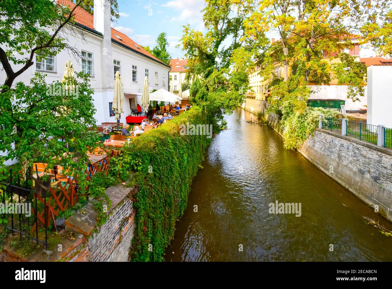 Ein Café am Wasser mit Terrasse an einem der üppigen Gartenkanäle in der Kampa Insel in Prag, Tschechien. Stockfoto