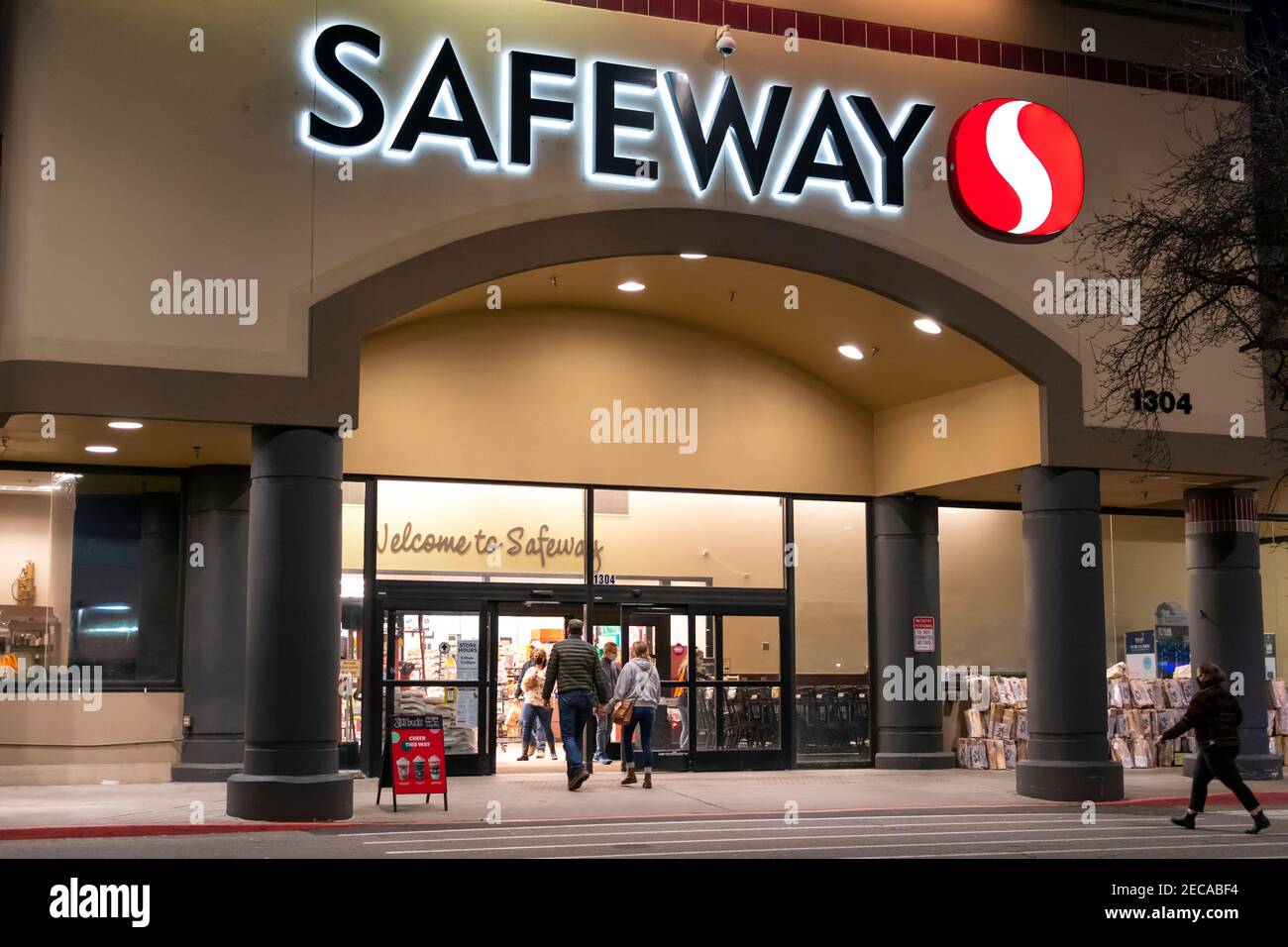 Die Käufer betreten nachts einen beleuchteten Safeway Supermarket-Supermarkt, der aufgrund des Maskenmandats Washingtons Masken trägt. Stockfoto