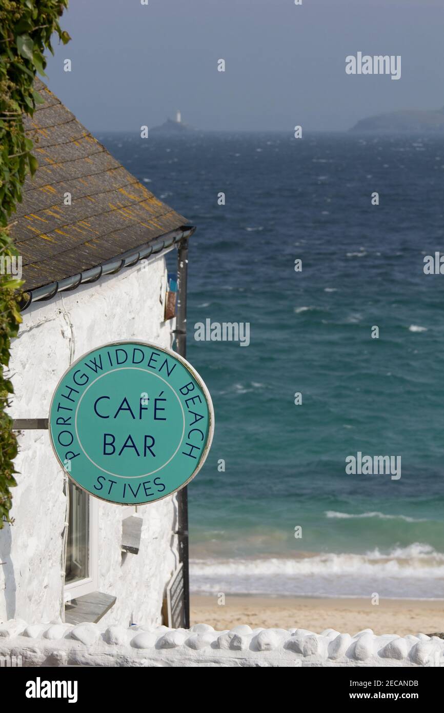 Porthgwidden Café mit Blick auf Porthgwidden Beach in St. Ives, Cornwall. Der Leuchtturm von Godrevy am Godrevy Point in der Ferne über die Bucht. Stockfoto
