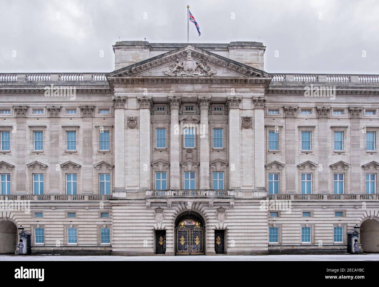 Die Fassade des Buckingham Palace mit Queens Footguard Soldaten im Dienst, Winterschnee, dunkle Wolken, London, Großbritannien Stockfoto