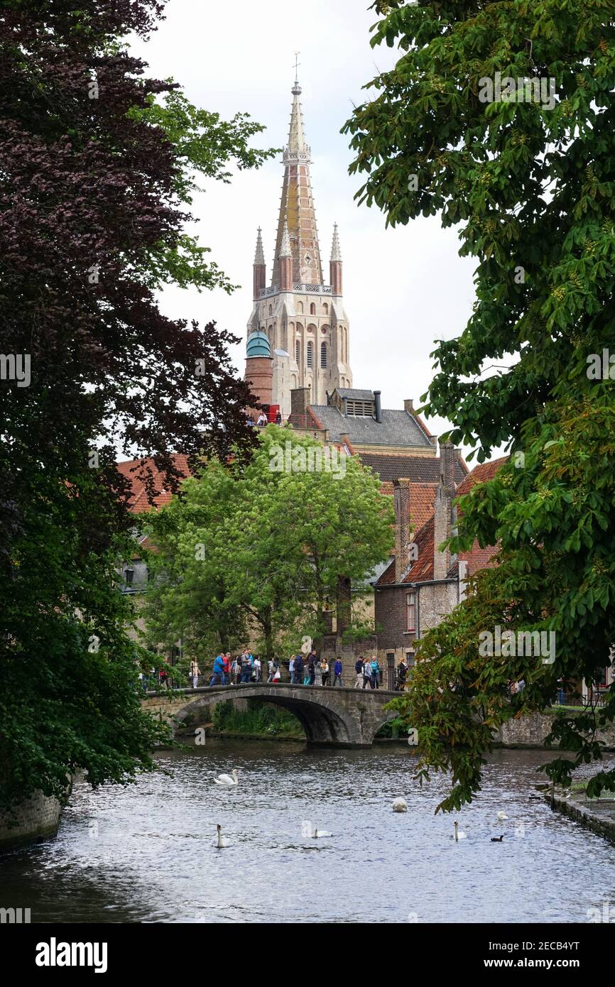 Touristen auf einer Brücke über den Bakkersrei-Kanal mit dem Turm der Liebfrauenkirche im Hintergrund, Brügge, Belgien Stockfoto