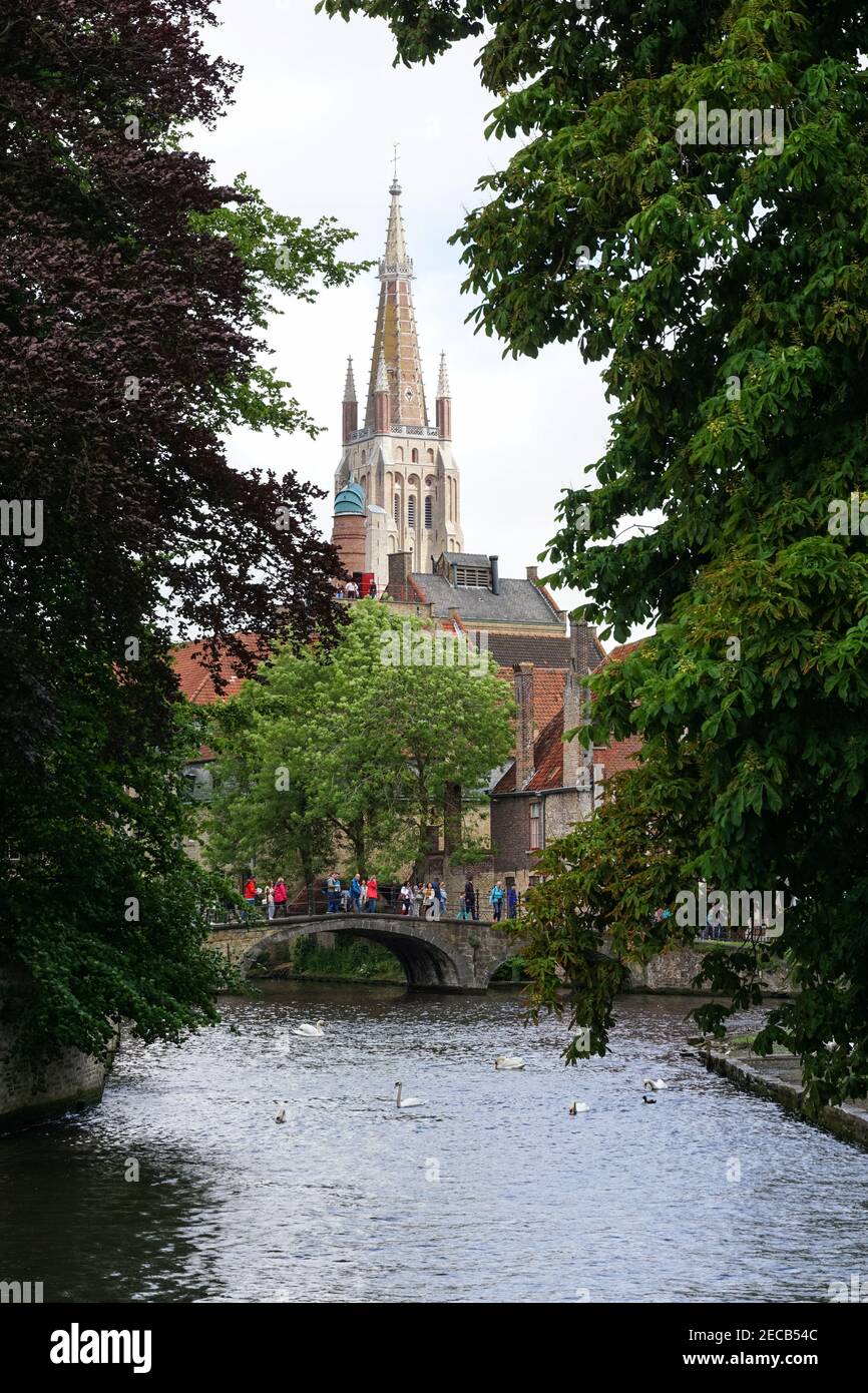 Touristen auf einer Brücke über den Bakkersrei-Kanal mit dem Turm der Liebfrauenkirche im Hintergrund, Brügge, Belgien Stockfoto