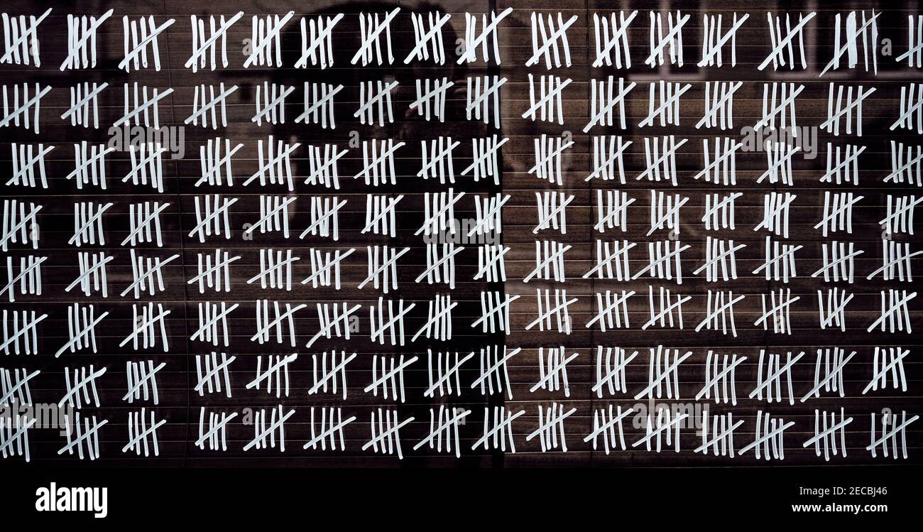 Handgemachte Tally-Markierungen, die von weißer Kreide an die Wand geschrieben wurden. Endloser pandemie-Lockdown, langjähriges Gefängnis, Warten auf den Sommer, alte Zählmethoden. Stockfoto