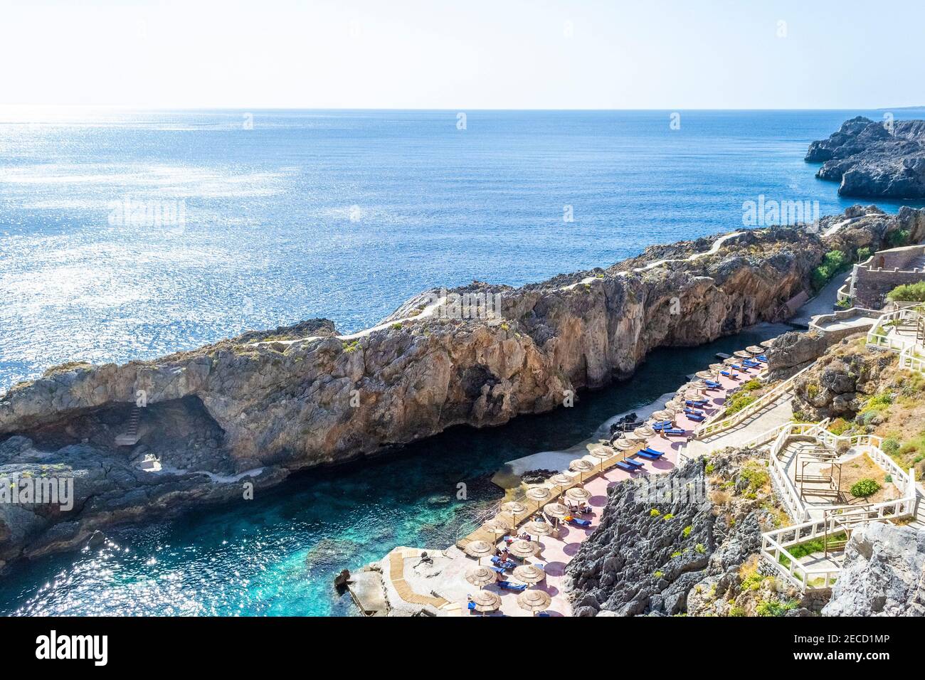Klippe am Meer und Bucht mit Sonnenschirmen, Kreta, Griechenland Stockfoto