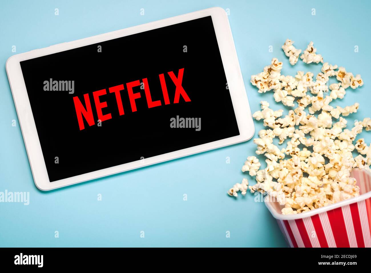 Netflix-Logo auf dem Bildschirm eines weißen digitalen Tablets Mit Popcorn auf blauem Hintergrund Stockfoto