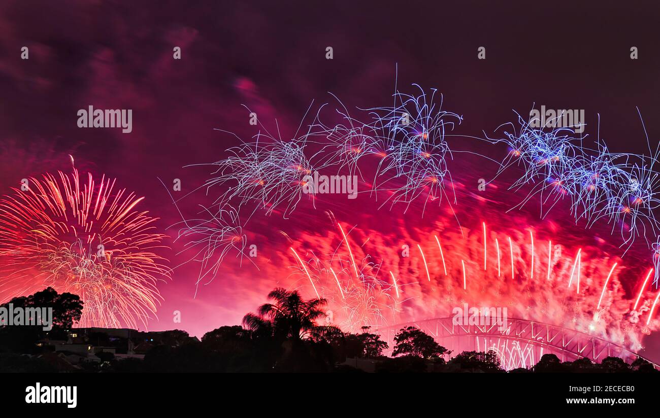 Tanzende Feuerbälle feuern einen Teil des Neujahrsfeuerwerks in Sydney über die Harbour Bridge in dunklem Nachthimmel. Stockfoto