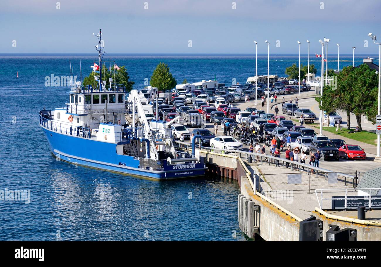 Touristen und Autos warten auf die Fähre Frau Chi-Cheemaun in South Baymouth, MANITOULIN Island, Georgian Bay. USGS-Vermessungsboot Sturgeon ist als Stockfoto