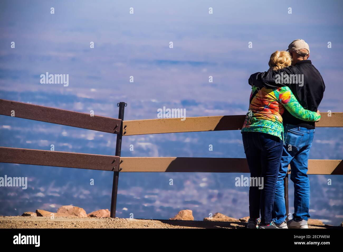 Ein älteres Paar steht mit den Armen umeinander Am Gipfel eines Berges, der auf einen herabblickt Panoramablick Stockfoto