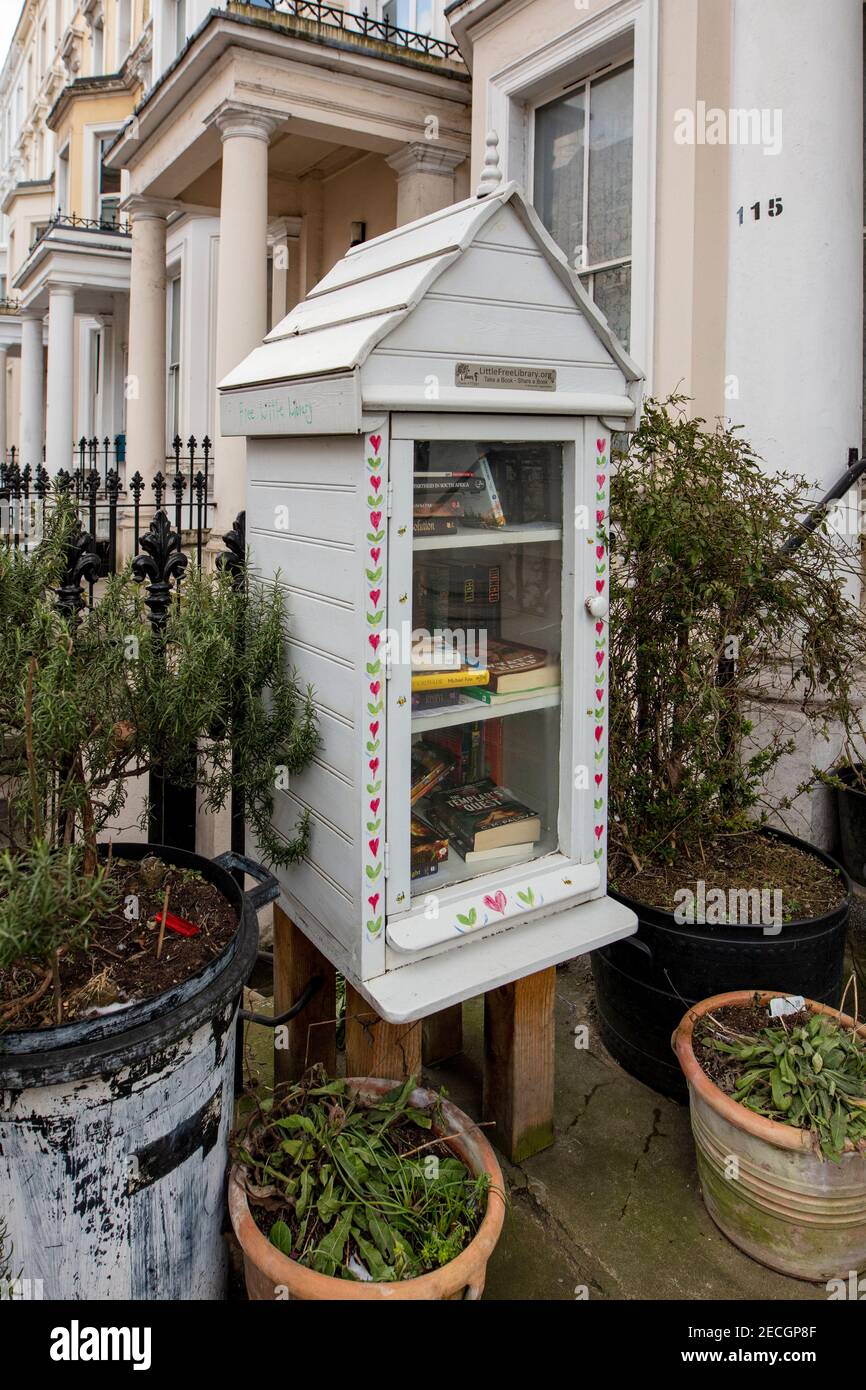 Kleine Leihbibliothek im Vorgarten in Kensington, London; die Leute werden gebeten, ein Buch auszuleihen und durch ein anderes zu ersetzen. Stockfoto