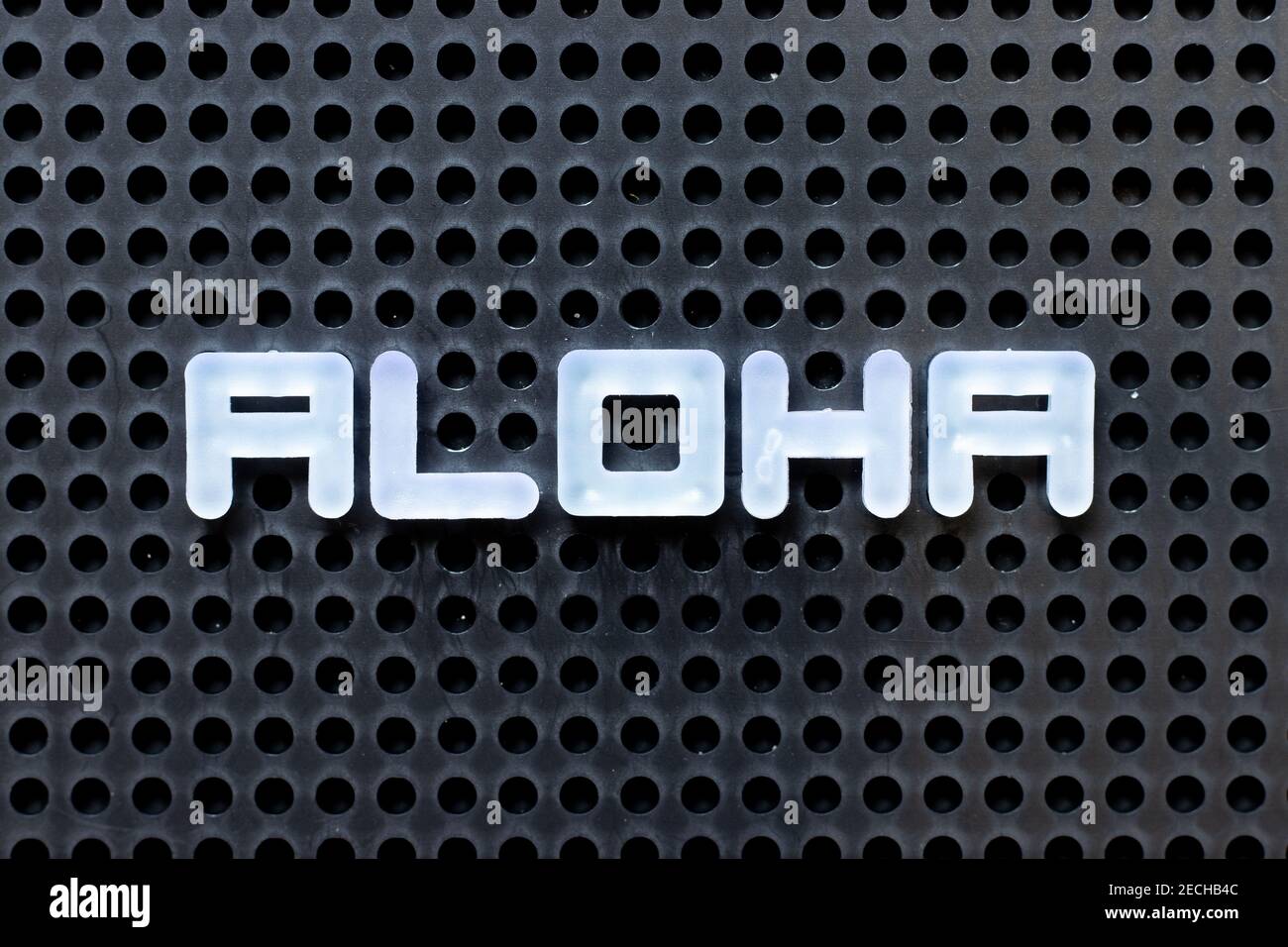 Weißes Alphabet mit Wort Aloha auf schwarzem Pegboard Hintergrund Stockfoto