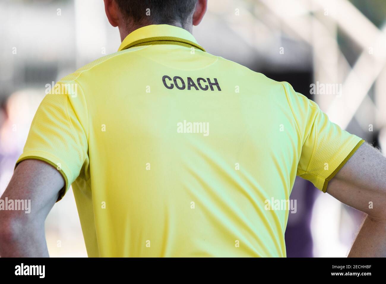 Rückseite des männlichen Trainer trägt gelbe TRAINER-Shirt beobachten sein Team konkurrieren, gut für Sport oder Coaching-Konzept Stockfoto