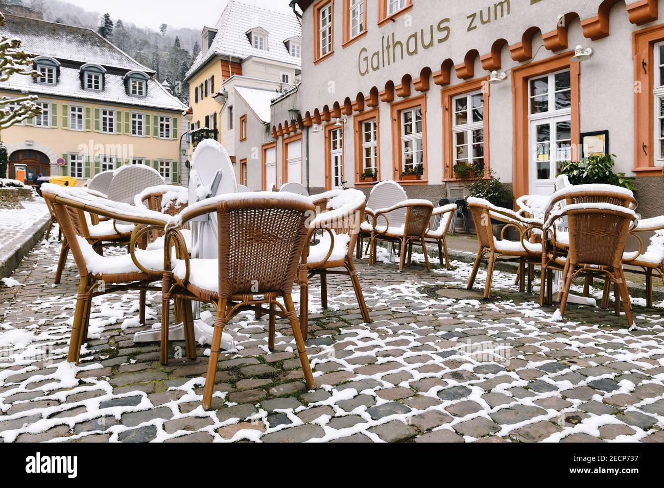 Heidelberg, Deutschland - Februar 2020: Leere Tische mit schneebedeckten Stühlen vor dem Restaurant im historischen Stadtzentrum von Heidelberg Stockfoto