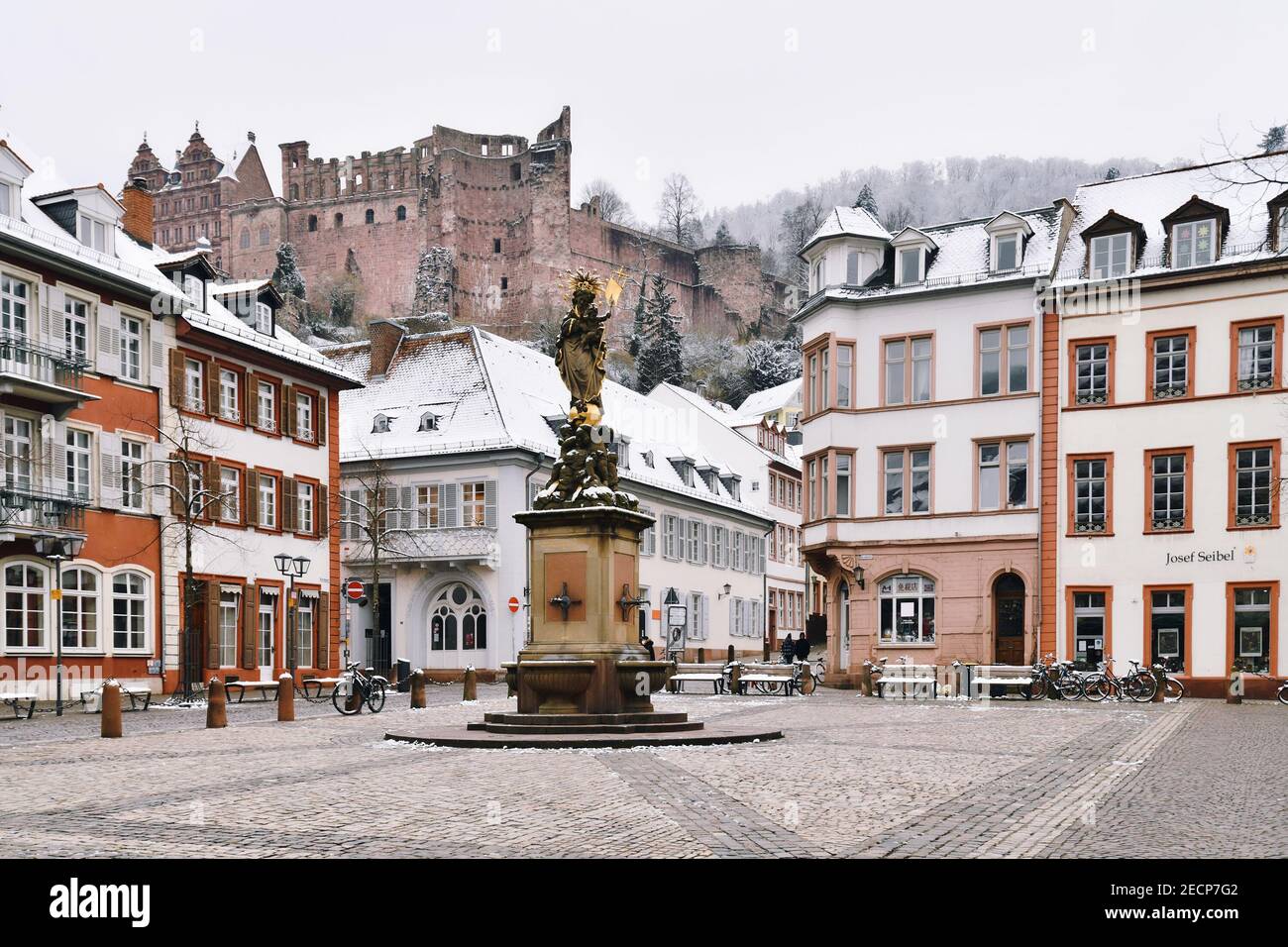 Heidelberg, Deutschland - Februar 2020: Alter Kornmarkt in der Altstadt mit Brunnen und Blick auf das historische Heidelberger Schloss mit Schnee Stockfoto