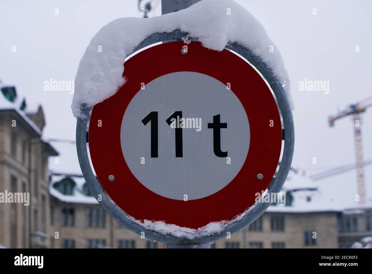Verkehrszeichen Begrenzung von 11 Tonnen mit Neuschnee bedeckt. Stockfoto