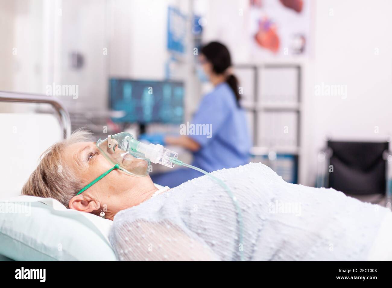 Ältere Frau mit Atemwegserkrankung wegen covid19 mit Sauerstoffmaske. Patient im Krankenhauszimmer, der während einer Coronavirus-Pandemie auf einem medizinischen Bett mit infizierter Lunge liegt und ein Atemproblem hat. Stockfoto