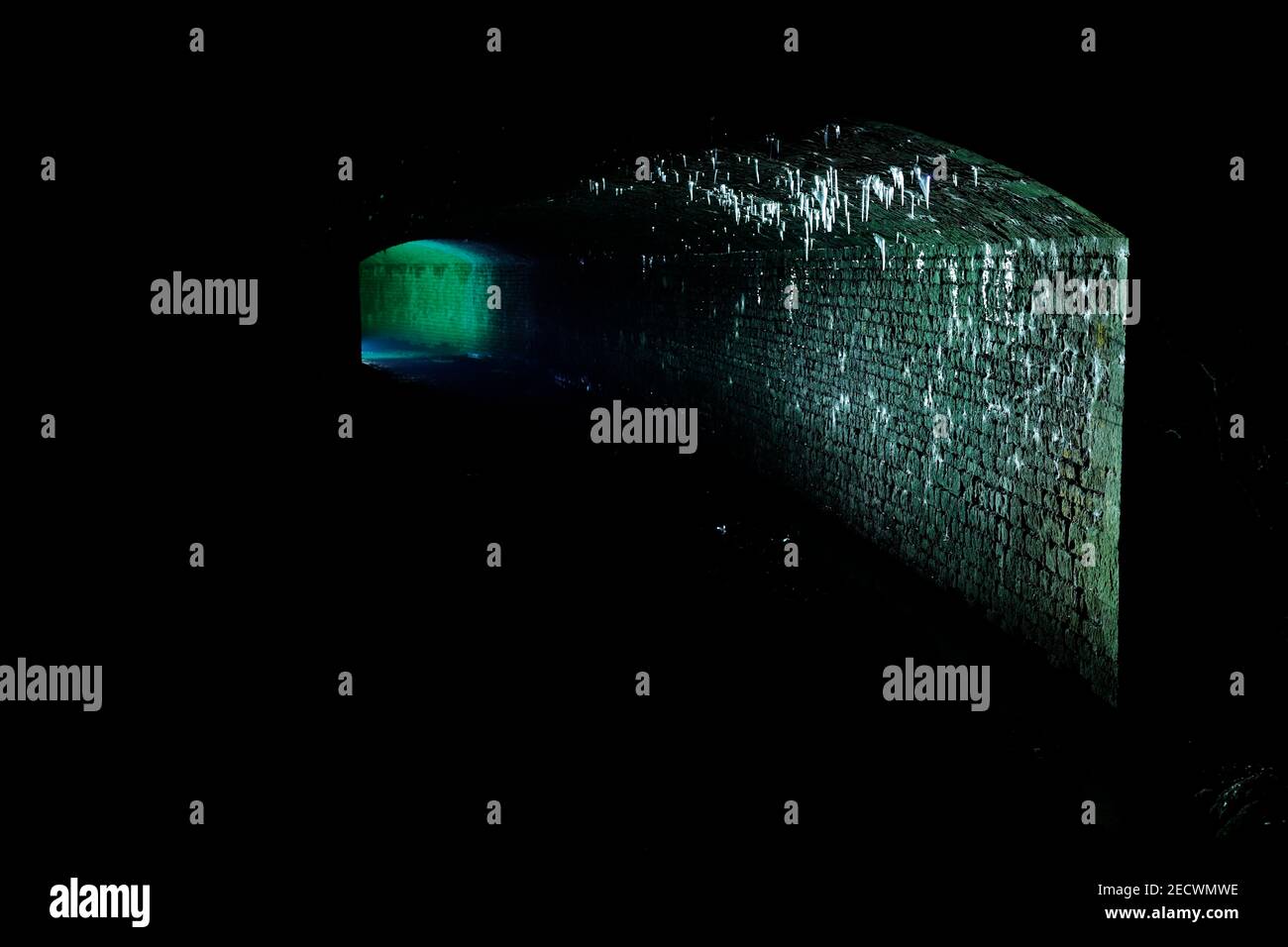 Bekannt als 'The Dark Arch' in der Nähe von Aberford in Leeds. Der Tunnel wurde mit einer Fackel beleuchtet, um die Eiszapfen vom Dach zu zeigen. Stockfoto