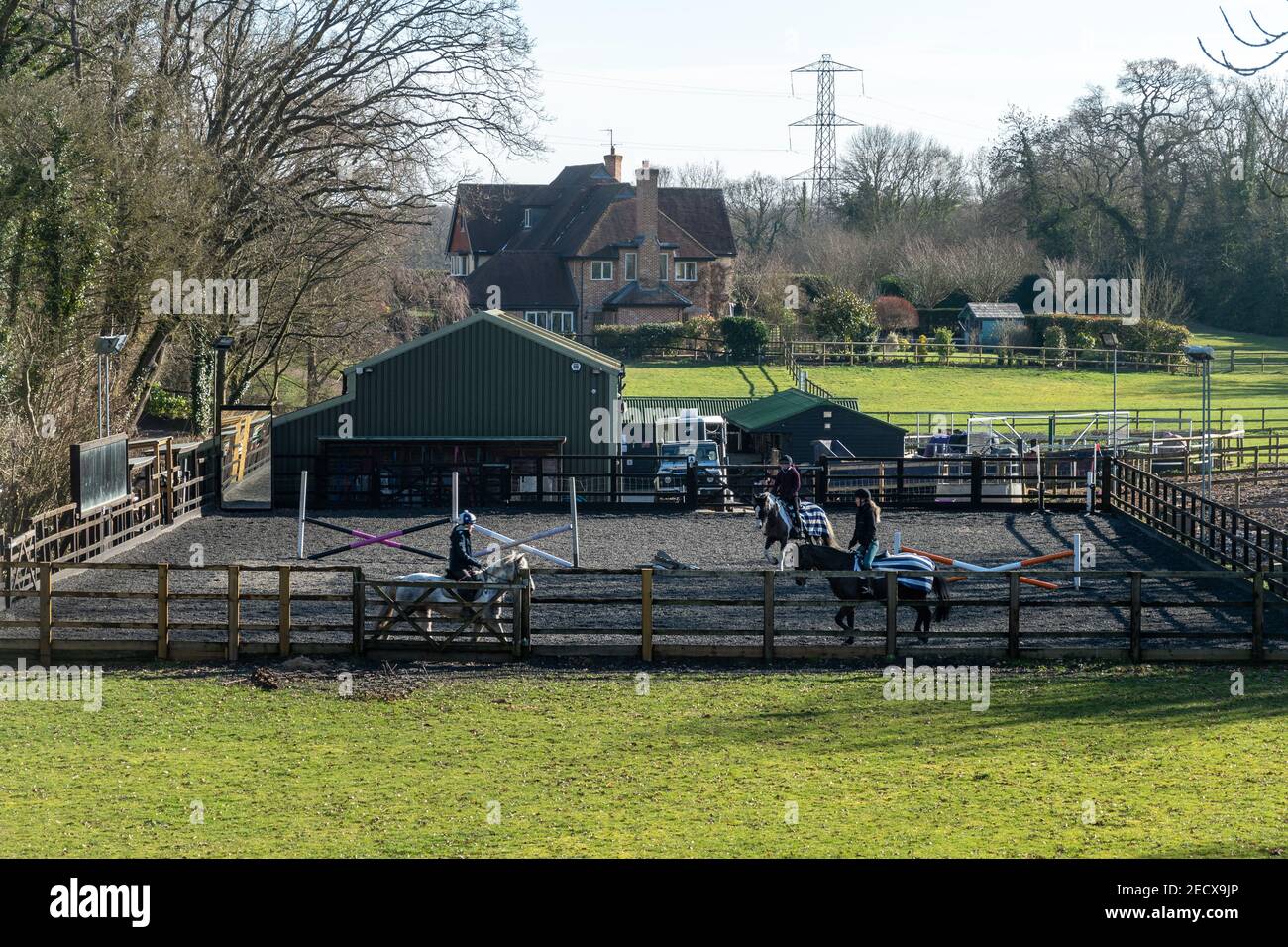 Outdoor-Reitplatz in der Reitschule mit drei Reitern auf Pferden, Hampshire, England, Großbritannien Stockfoto