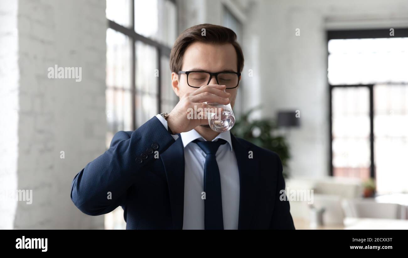 Durstiger Mann trinkt sauberes Mineralwasser aus Glas Stockfoto