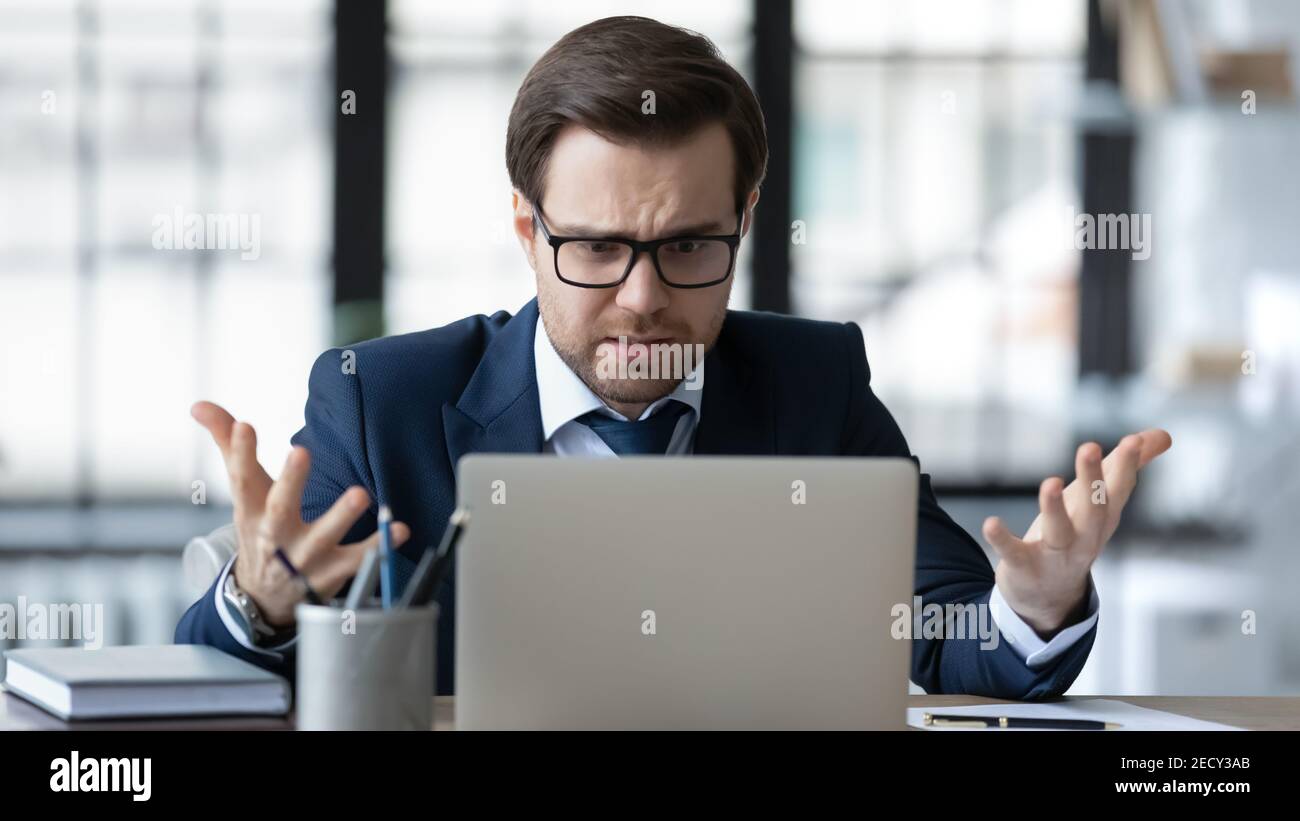 Verärgerte männliche CEO frustriert durch Online-Probleme arbeiten auf Laptop Stockfoto