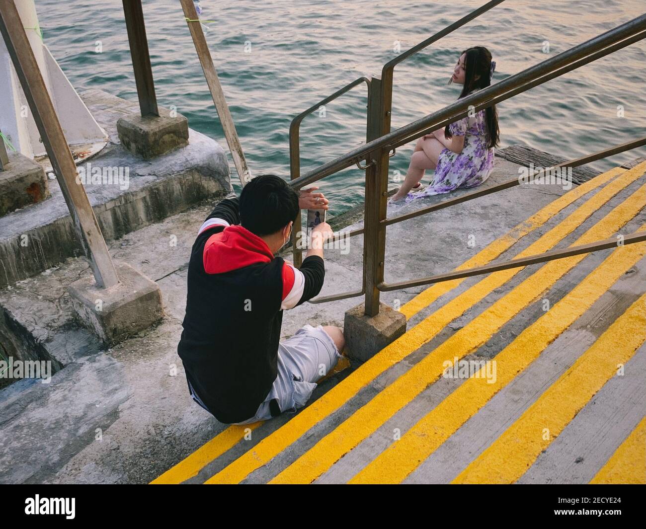 Ein Paar fotografiert vor dem Meer in der Nähe der Tsing Ma Brücke. Am Valentinstag feiern die Menschen unter dem Einfluss von COVID-19. Viele entscheiden sich, mit ihren Lieben auf dem Land zu verbringen, wo sie weniger Menschen sind, um eine bessere soziale Distanzierung zu geben. Stockfoto
