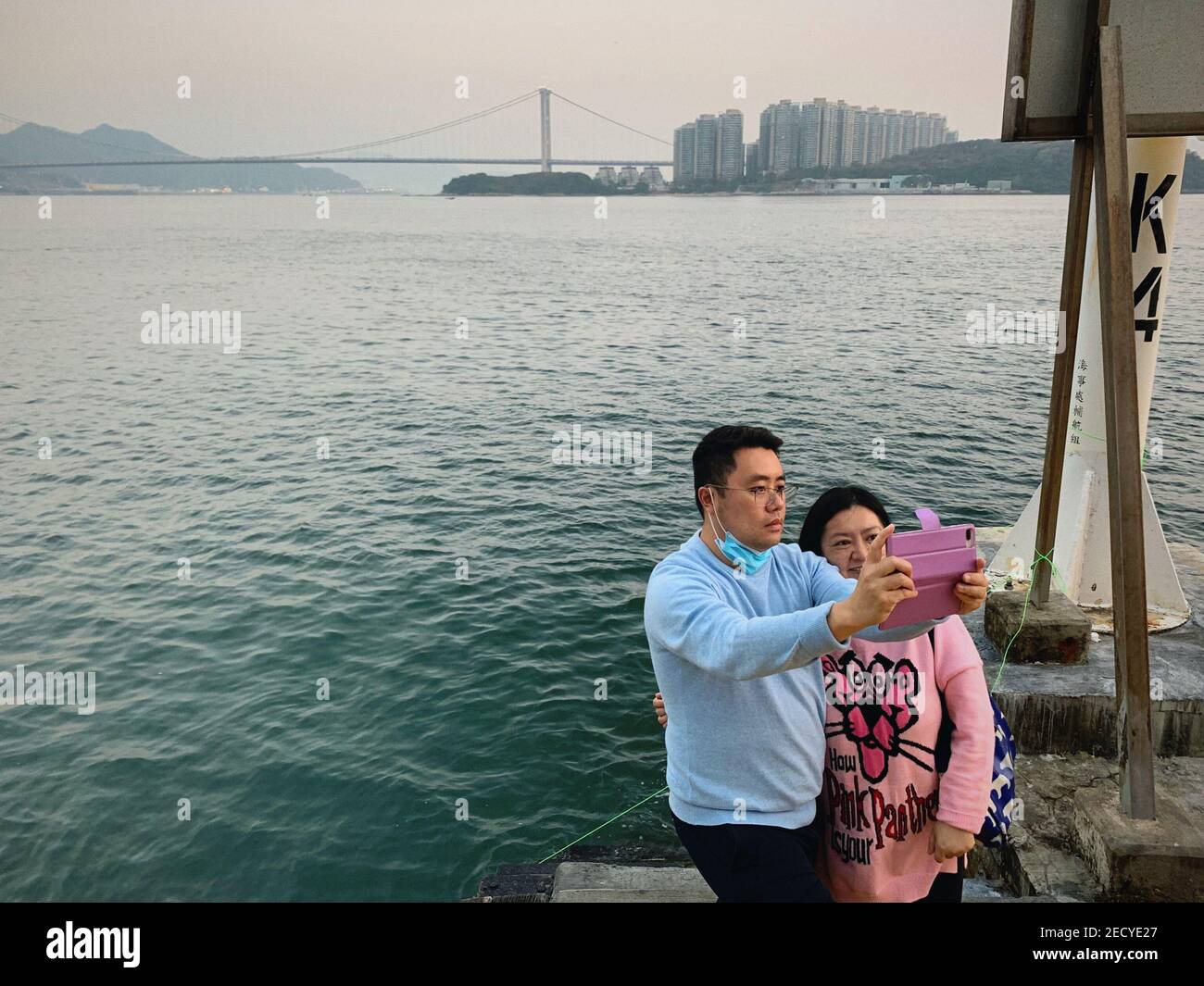 Ein Paar macht Selfie vor dem Meer in der Nähe der Tsing Ma Brücke. Am Valentinstag feiern die Menschen unter dem Einfluss von COVID-19. Viele entscheiden sich, mit ihren Lieben auf dem Land zu verbringen, wo sie weniger Menschen sind, um eine bessere soziale Distanzierung zu geben. Stockfoto