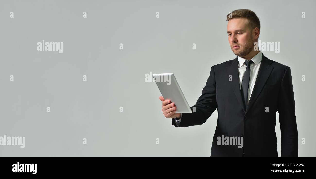 Geschäftsleute, die aufmerksam auf einem digitalen Tablet auf grauem Hintergrund blicken Stockfoto