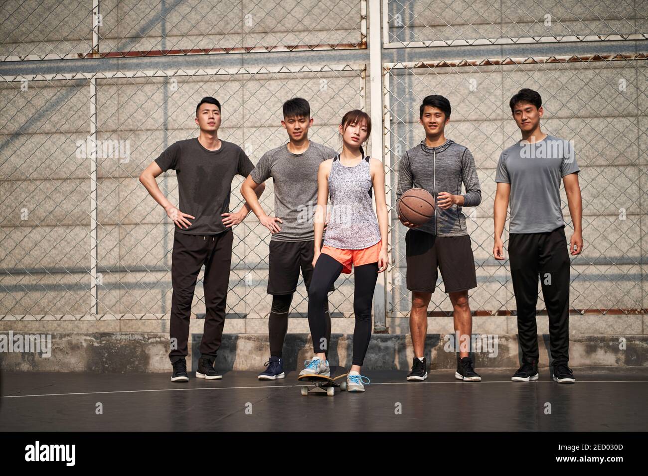 Hipster junge asiatische Frau posiert im Freien mit Skateboard und vier männlichen Freunden Stockfoto