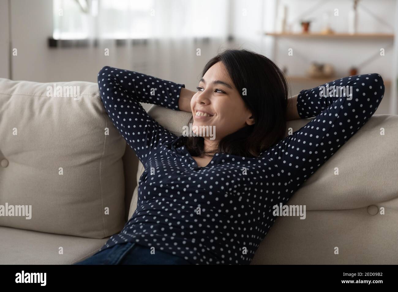 Junge glückliche vietnamesische Frau Rest auf Couch Traum visualisieren Erfolg Stockfoto