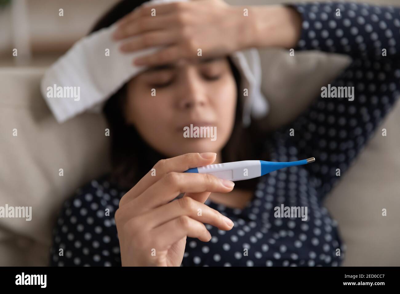 Konzentrieren Sie sich auf elektronische Thermometer in der Hand der kranken asiatischen Frau Stockfoto