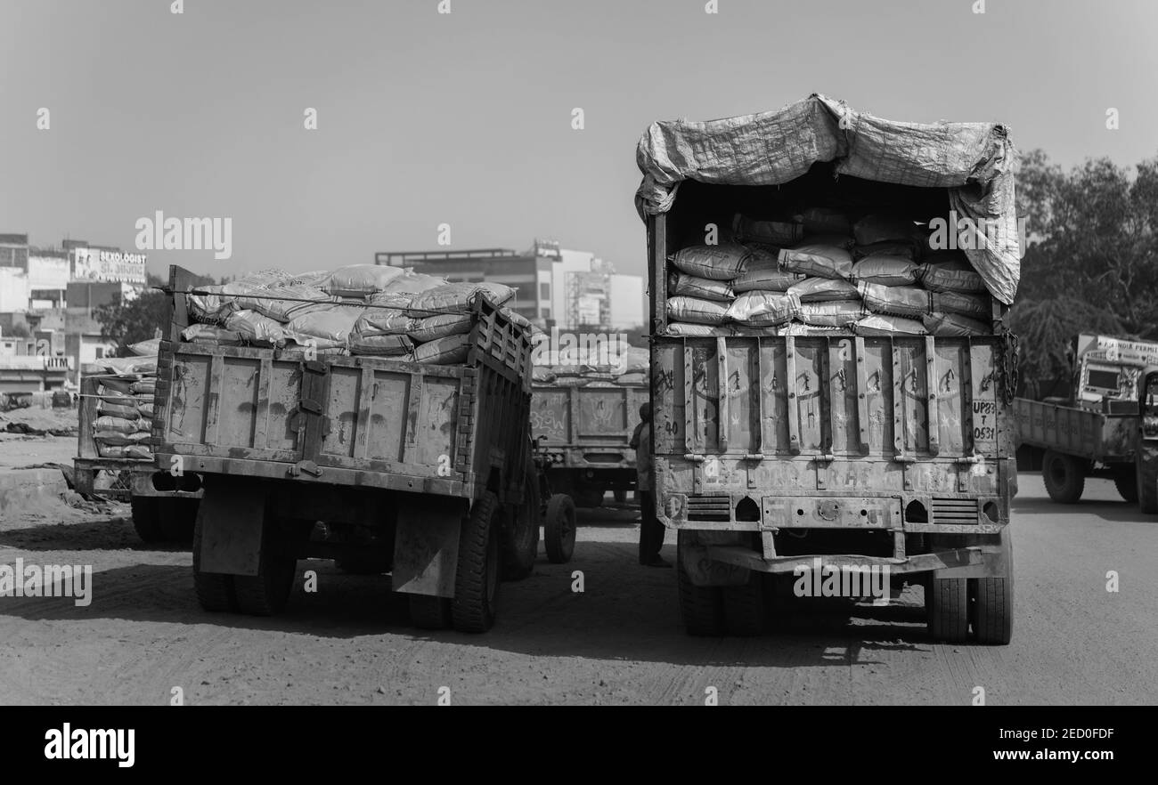 Schwere Zementsäcke von Hand vom Zug zu wartenden LKWs bei heißem, staubigen Bedingungen in Mathura, Uttar Pradesh, Indien. Stockfoto
