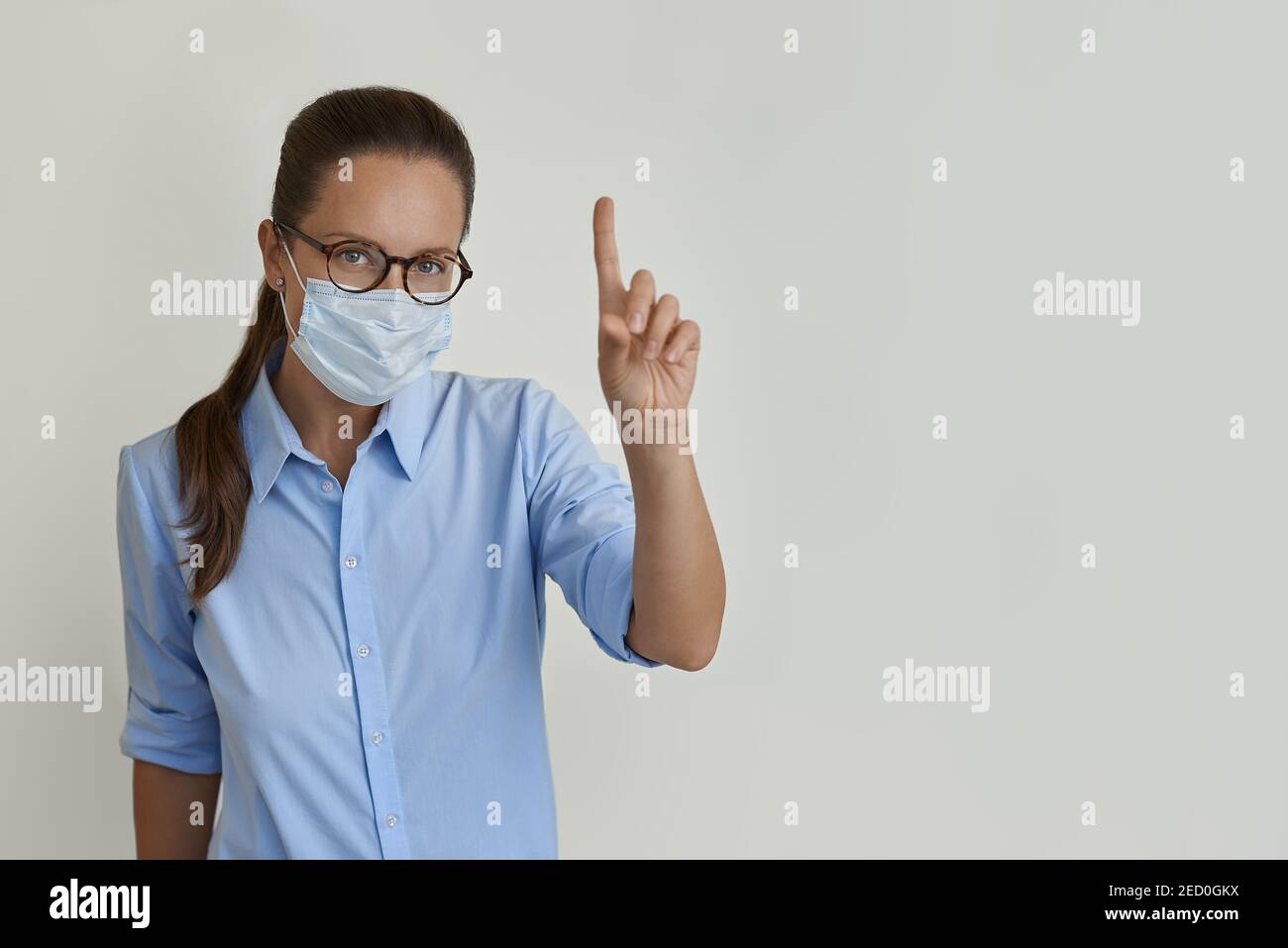 Frau in medizinischer Maske zeigt ihren Finger Stockfoto