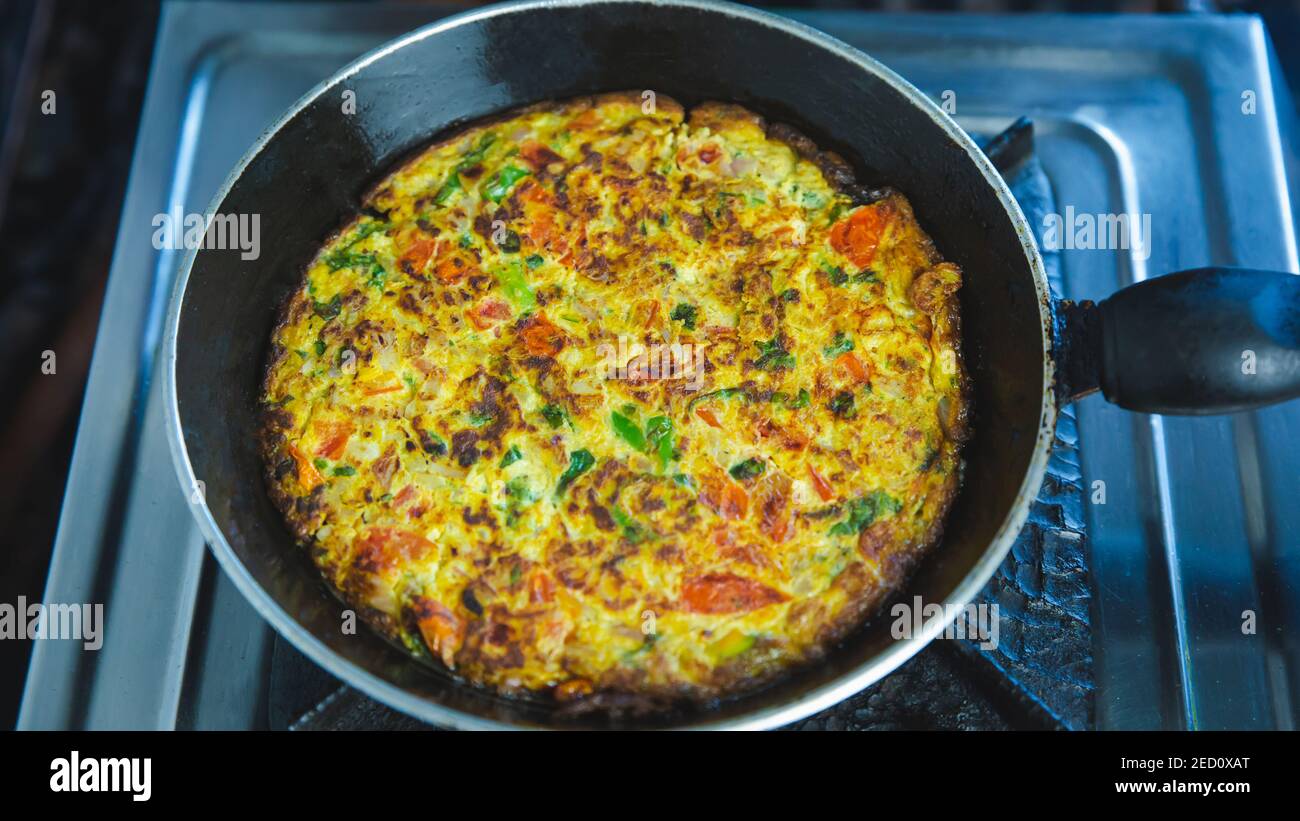 Gebratene Veggie Omelette mit Gemüse in einer Pfanne auf dem Gasherd verrühren. Indischer Nepalesischer Stil Masala Omelett Stockfoto