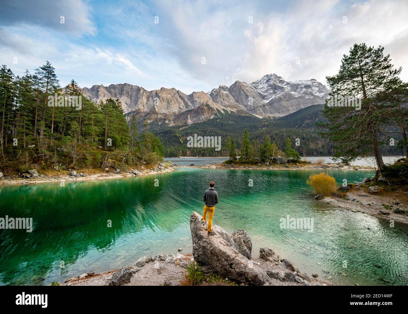 Junger Mann steht auf einem Felsen am Ufer, Blick in die Ferne, Eibsee vor Zugspitzmassiv mit Zugspitze, Wettersteingebirge, in der Nähe Stockfoto