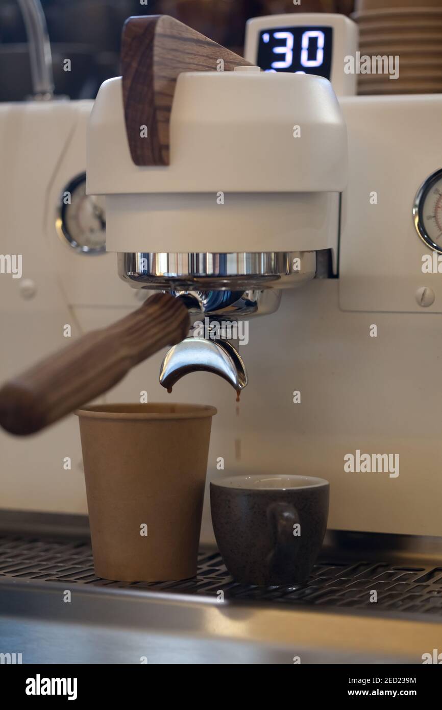 Nahaufnahme der modernen professionellen Espressomaschine im Café mit Kaffeeausguss in Take Away Pappbecher, niemand Stockfoto