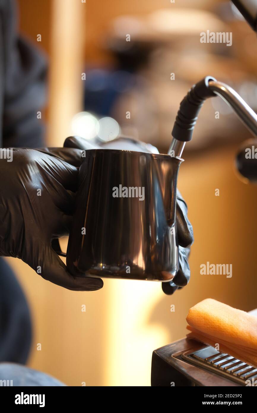Barista Hände dämpfen Milch für Kaffee in modernen Espressomaschine, Nahaufnahme Stockfoto
