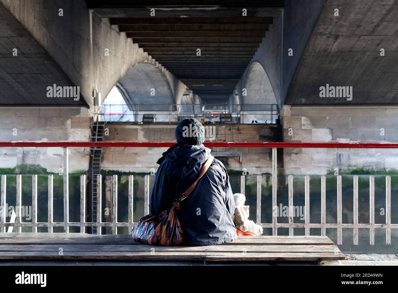 Einsame Frau, die unter der Waterloo Bridge in London sitzt Stockfoto