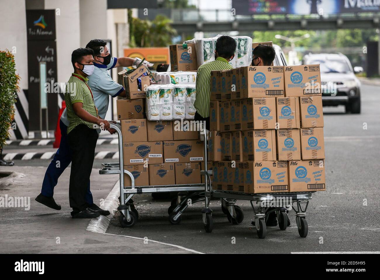 Arbeiter organisieren Waren auf Karren vor einem Lebensmittelgeschäft. Die philippinische Wirtschaft stürzte in eine Rezession, als sie sich mit den steigenden Coronavirus-Infektionen auseinandersetzt. Quezon City, Metro Manila, Philippinen. Stockfoto