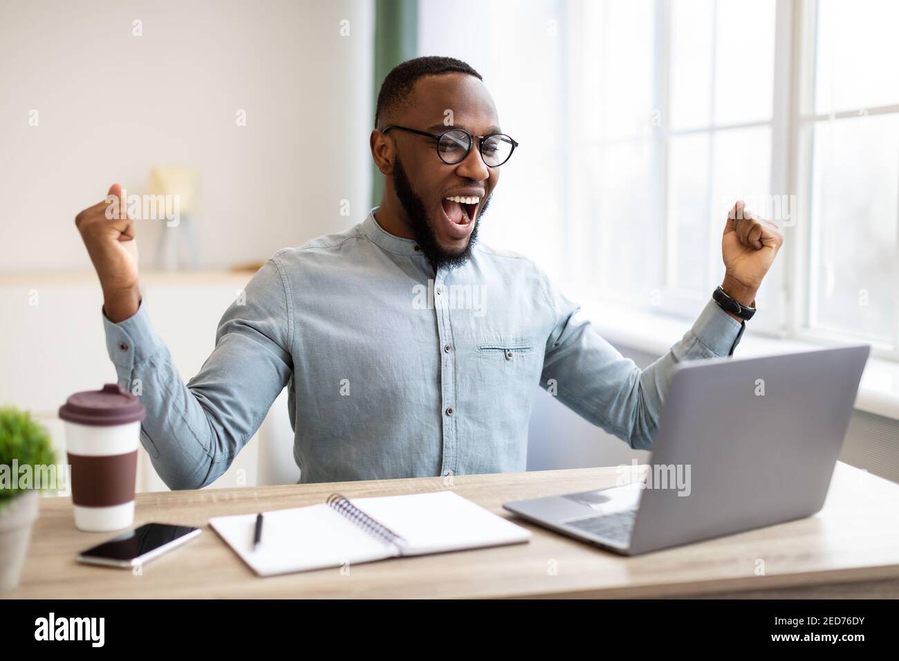 Afrikanischer Geschäftsmann Am Laptop Schüttelt Fäuste Schreien In Joy Indoor Stockfoto