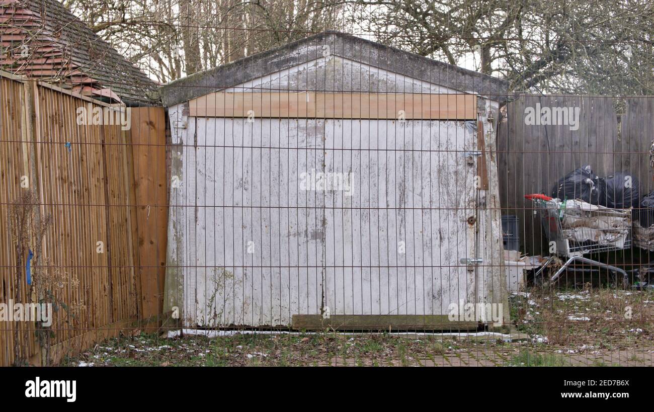 Schäbige alte Scheune oder Garage hinter Zaun mit weggeworfenen Einkaufskassewagen Stockfoto