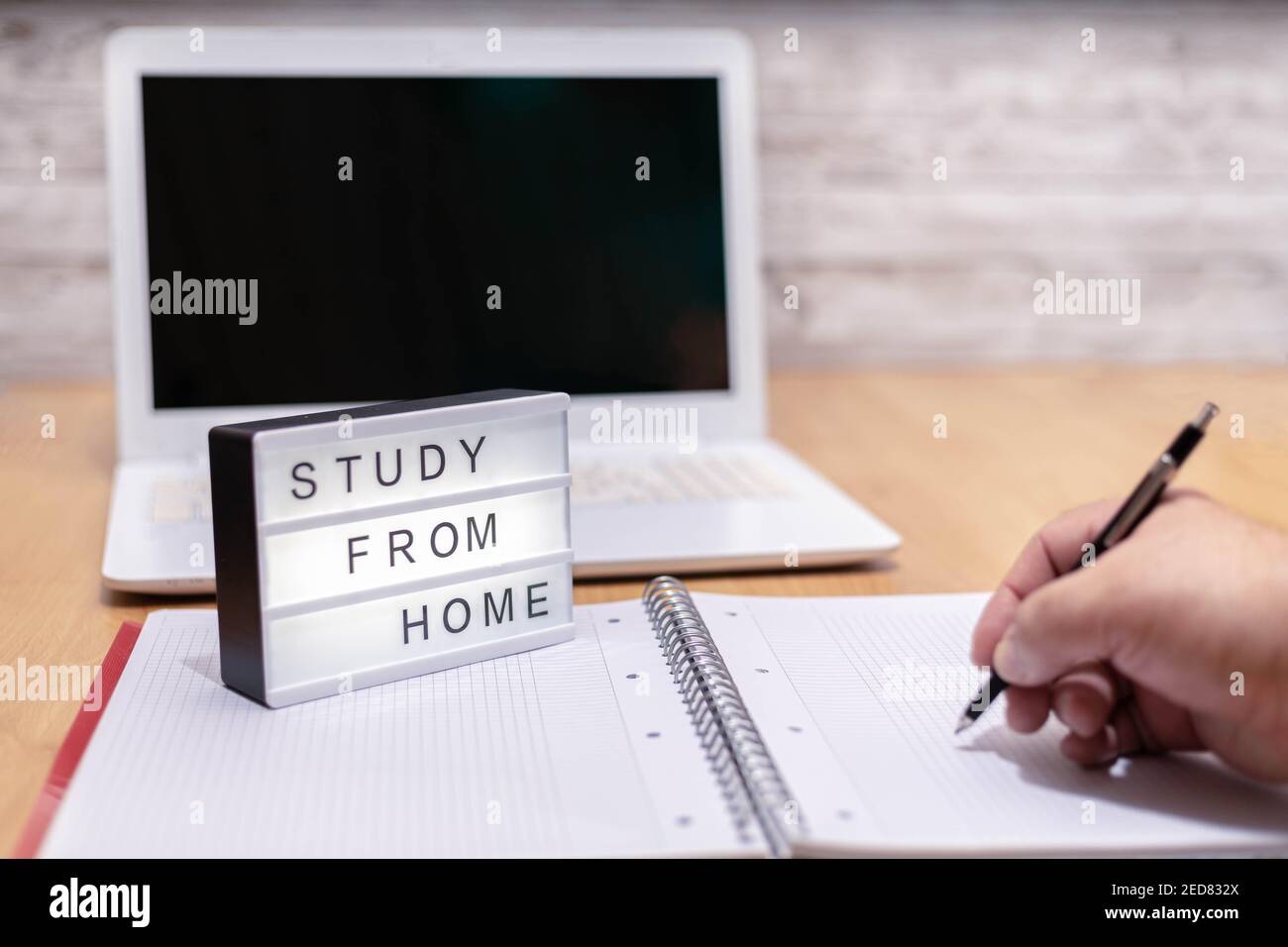 Selektiver Fokus einer Person mit Notebook und Stift Aufgaben mit einem Leuchtfeld, das auf „Home Study with Laptop“ hinweist Computer im Hintergrund in CO Stockfoto