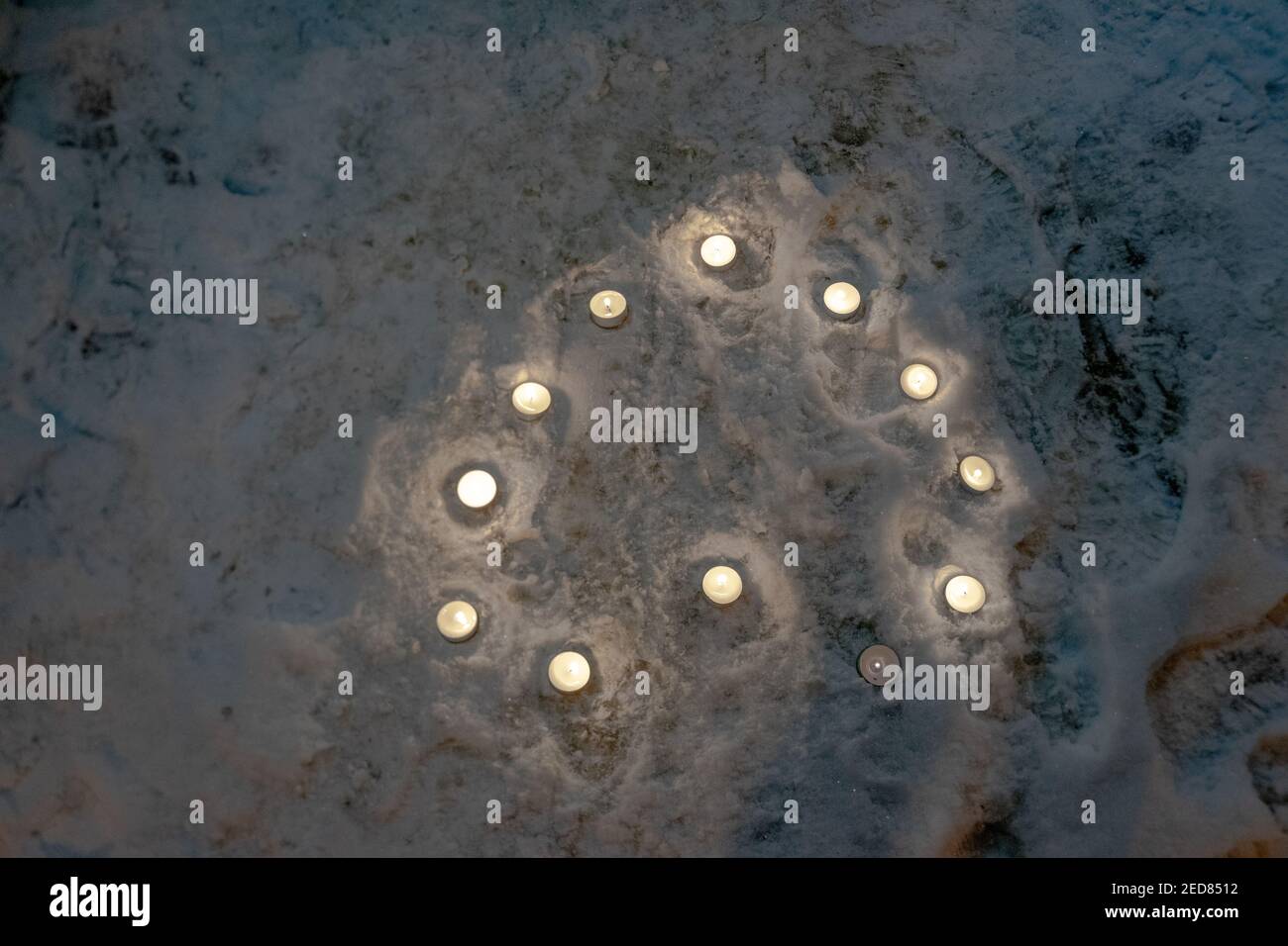Kleine runde Kerzen, die das Herz umreißen Schnee in der Nacht Stockfoto