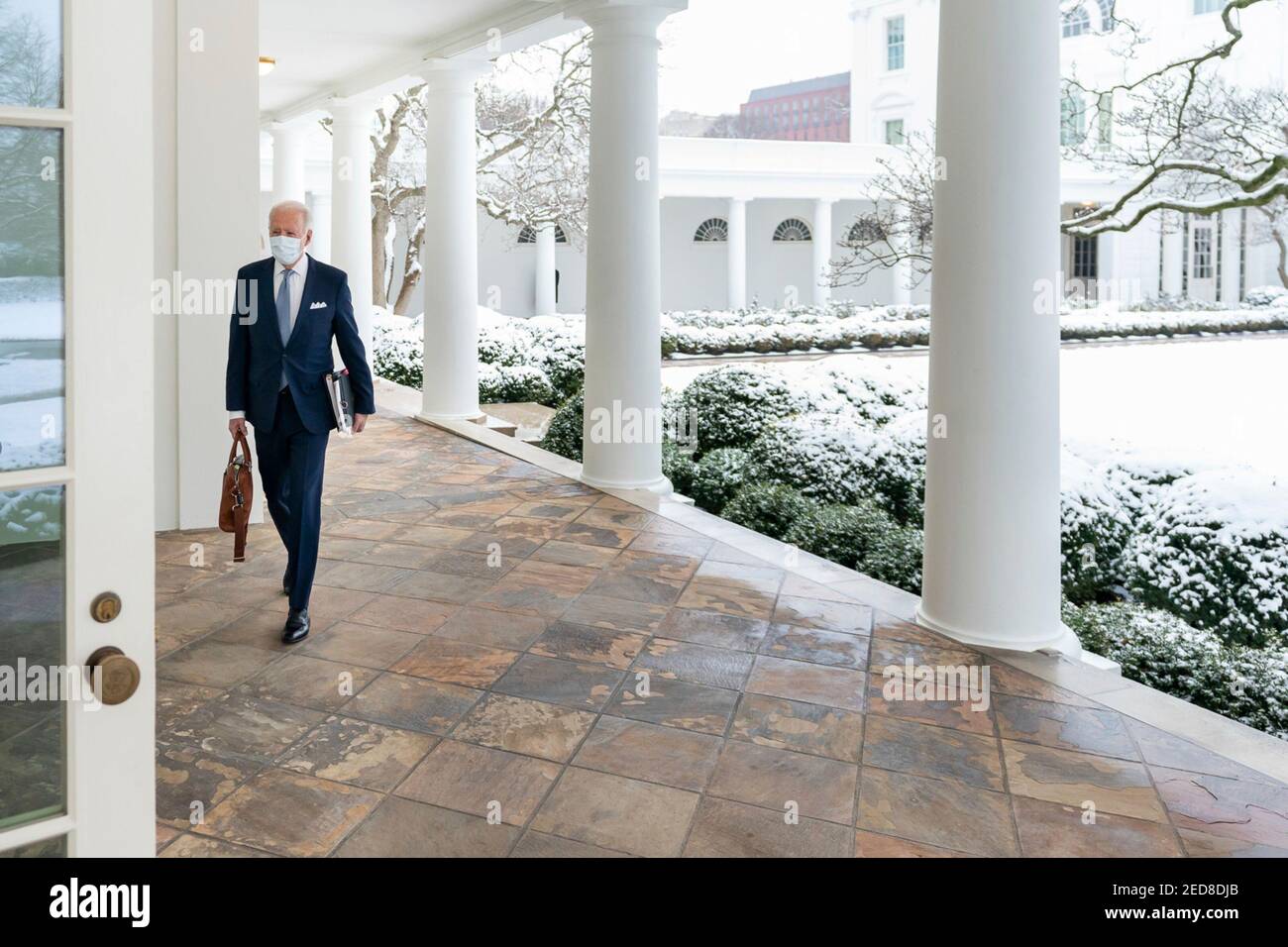 Eine Schneedecke bedeckt den Rosengarten des Weißen Hauses, während US-Präsident Joe Biden entlang der Kolonnade zum Oval Office am 1. Februar 2021 in Washington, D.C., spaziert. Stockfoto