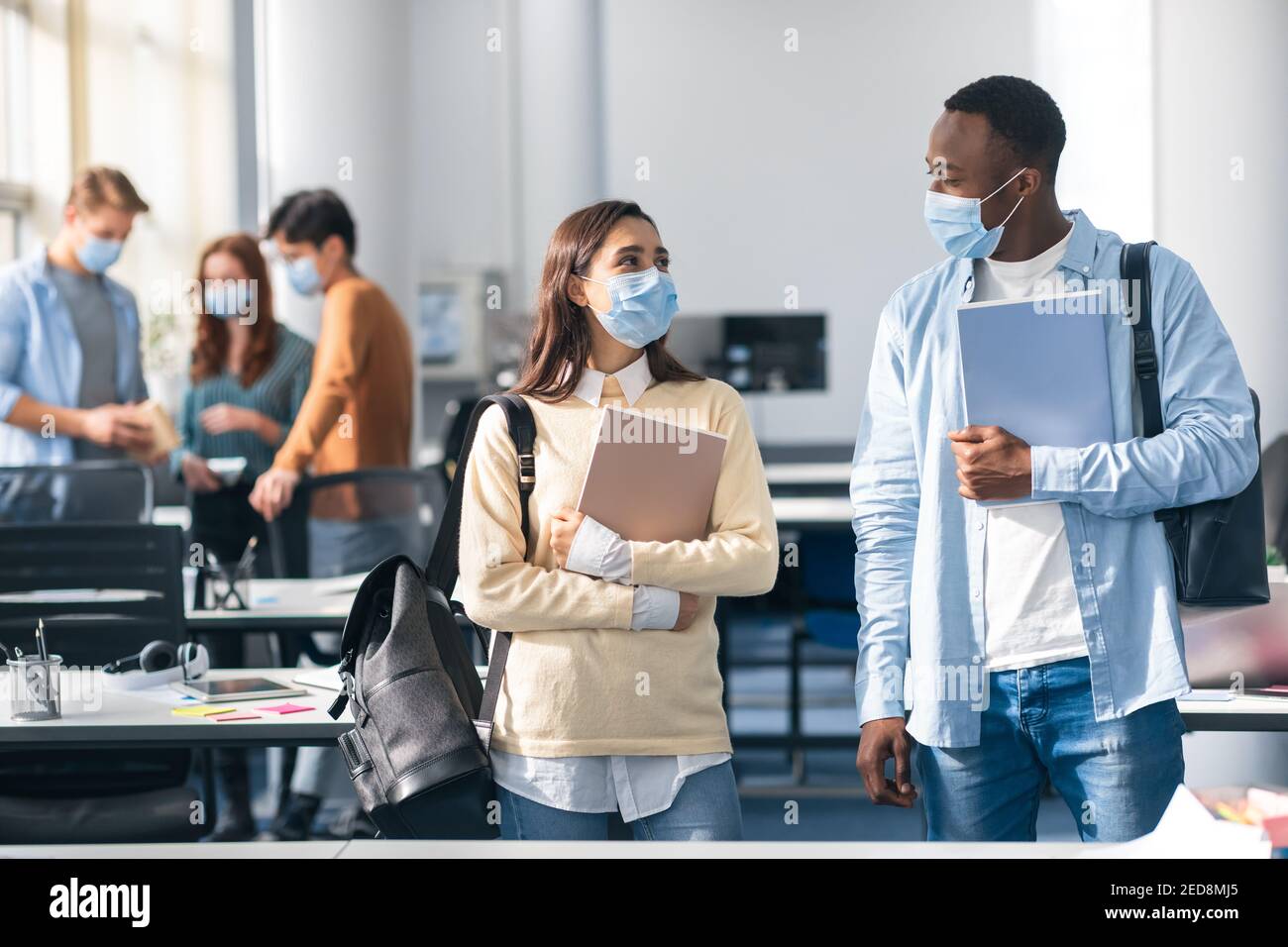 Internationale Studenten tragen medizinische Gesichtsmasken und reden Stockfoto