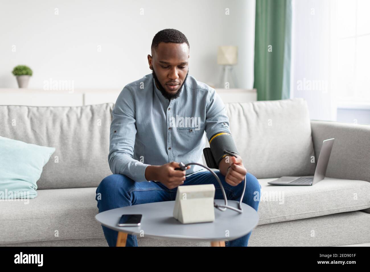 Afrikanischer Mann, Der Arteriellen Blutdruck Misst, Sitzt Zu Hause Stockfoto