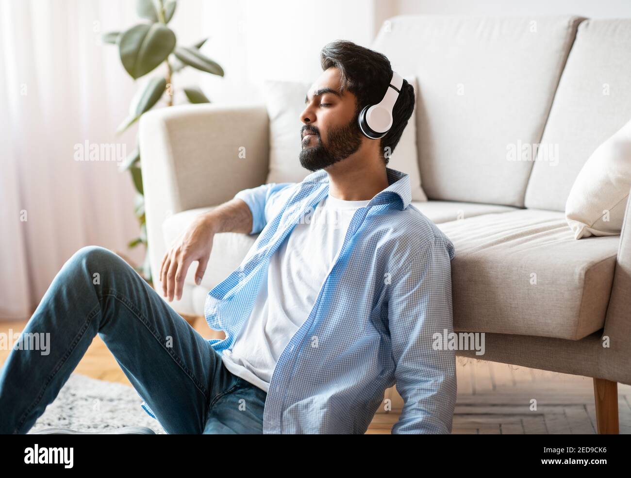 Zeit Zum Entspannen. Ruhiger arabischer Mann mit Kopfhörern, der zu Hause Musik hört Stockfoto