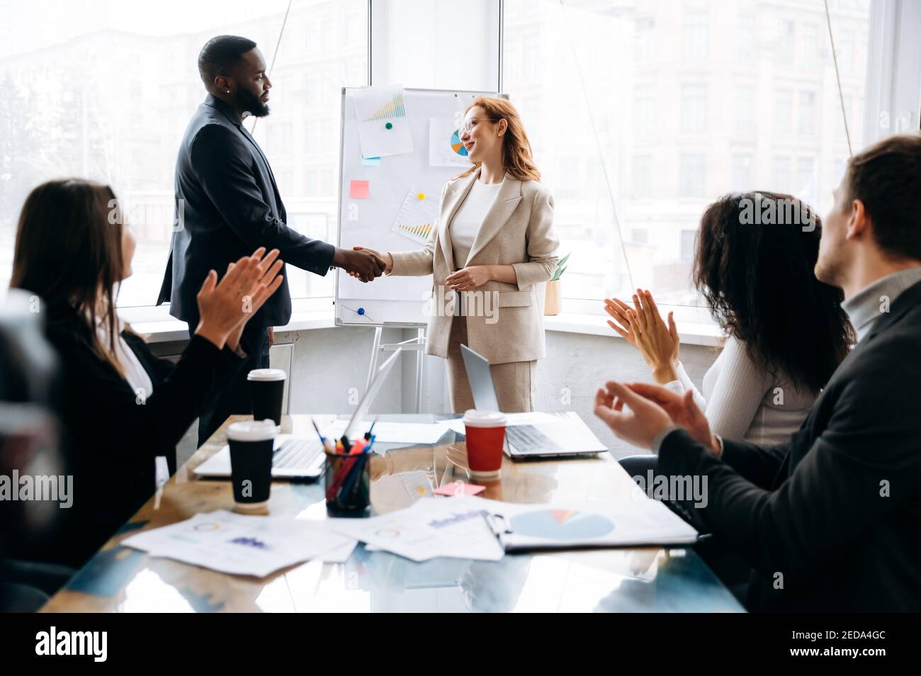 Geschäftspartner bei Verhandlungen. Multiethnische Teams treffen beim Briefing-Meeting eine Einigung. afroamerikanischer männlicher Chef schüttelt sich die Hände mit kaukasischer weiblicher Kollegin, unterzeichnet einen Vertrag, Kollaborationskonzept Stockfoto