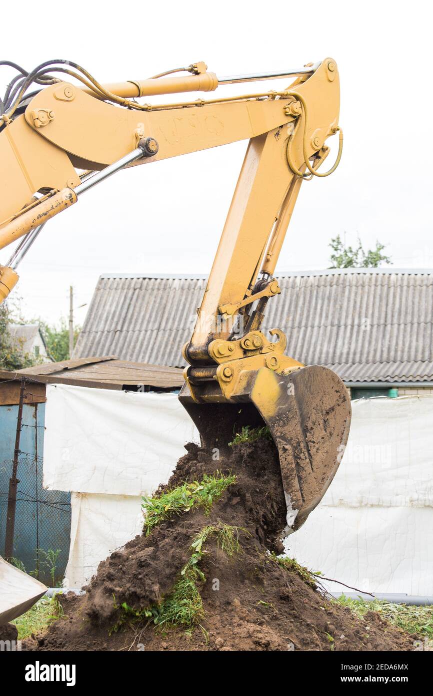 Aushubarbeiten in der Industrie. Ein Bulldozer gießt einen Eimer Land auf einer Baustelle aus der Nähe. Stockfoto