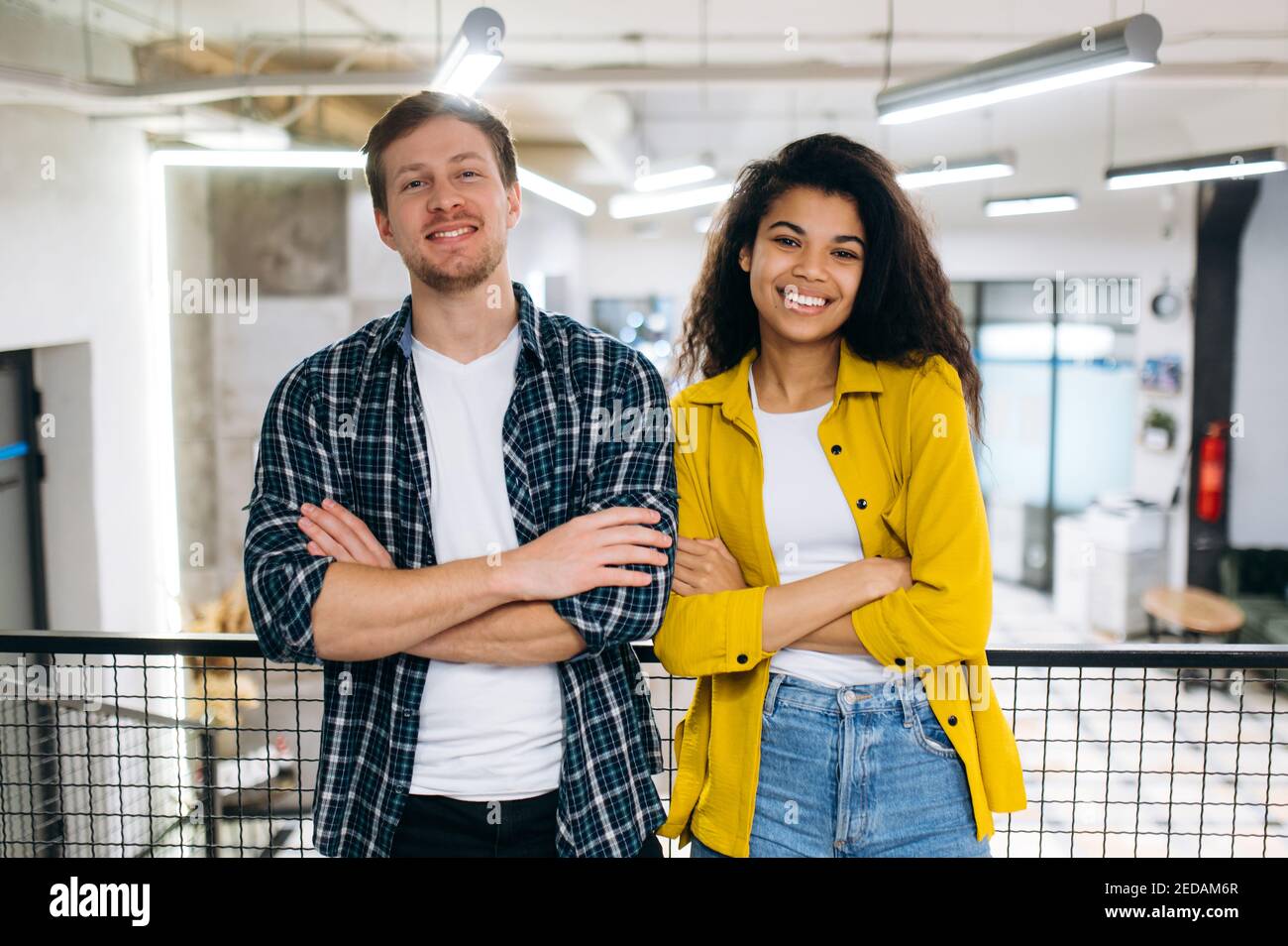 Porträt von Geschäftskollegen oder studentischen Freunden. Schöner kaukasischer Mann und schöne afroamerikanische Frau arbeiten oder studieren zusammen. Junge Erwachsene multirassische Kollegen schauen lächelnd auf die Kamera Stockfoto