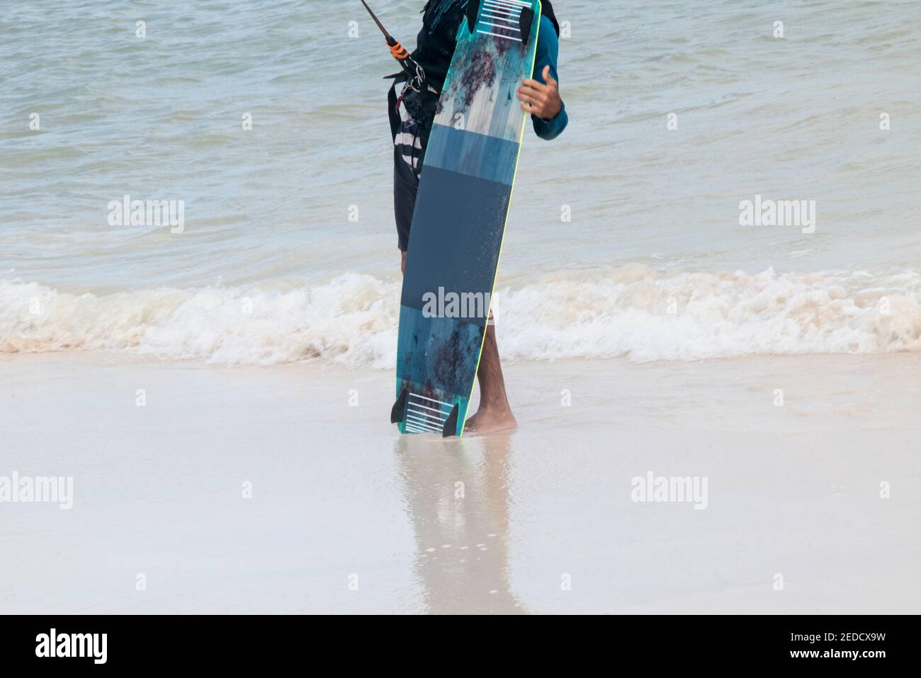 Ein Sportler hält vertikal ein Kite-Boarding-Board am Meer. Im Hintergrund das mexikanische Karibische Meer. Stockfoto