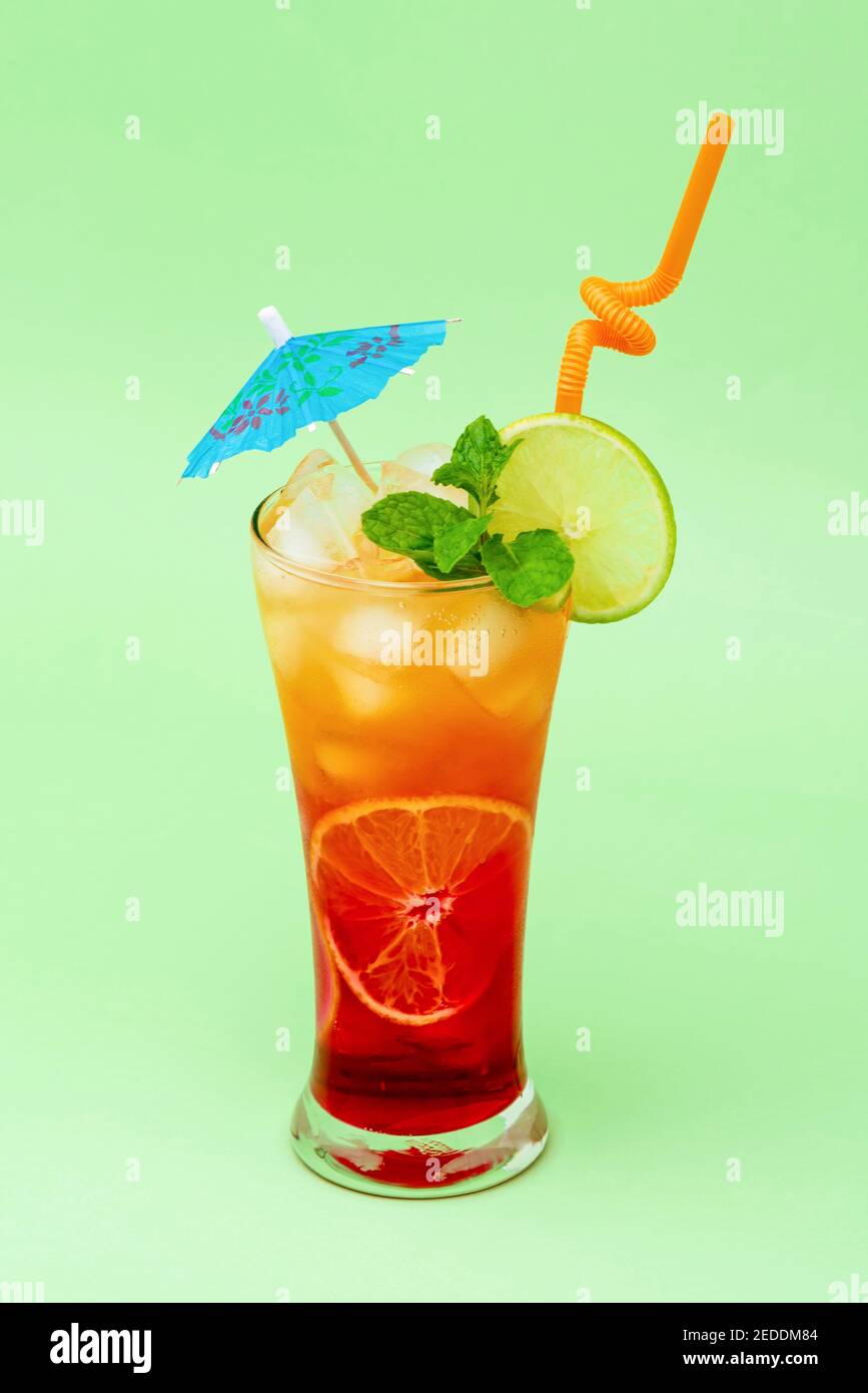 Buntes alkoholisches Cocktail-Getränk im Glas, dekoriert mit Limette, Minze und Regenschirm Stockfoto